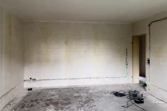 Wohnzimmer vor Renovierung. Rohe Wände, Boden ohne Belag